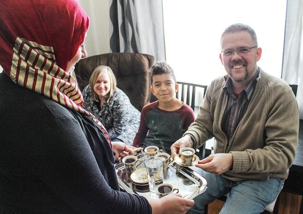 In a 2017 file photo, a Syrian refugee serves a tiny cup of expresso to Canadian minister Noel Walker, as Julie Walker and Mohammed smile at the camera. 