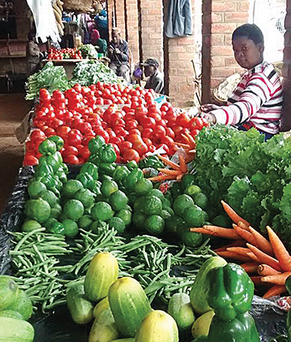 Piles of vegetables and fruits line the tables of an open-air market Zomba