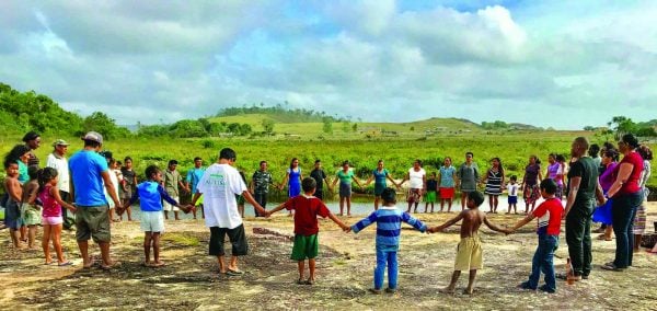 Hand in hand with children from the Monkey Mountain congregation, youths from the Amelia's Ward Church of Christ pray during their mission trip to Guyana's interior.
