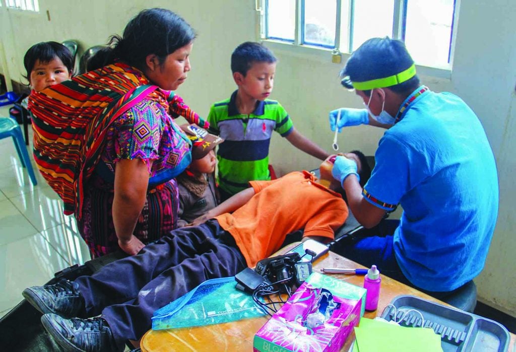 Mauricio chan, a worker with Health Talents International, checks the teeth of a child in the ministry's child-sponsorship program during a mobile medical clinic.