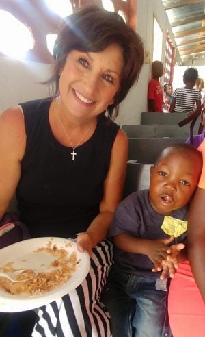 Debbie Dupuy helps feed a young boy his lunch.