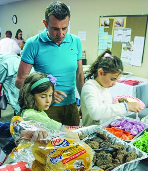 Horald Shabanaj and daughters Isabelle, 8, and Vanessa,10, fill their plates at a church fellowship meal.