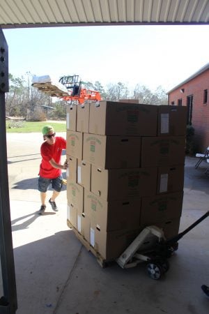 Corbin Cherry, 14, helps roll a stack of emergency food boxes from Churches of Christ Disaster Relief Effort into the Jenks Avenue church's family activity center.