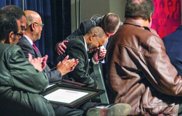 Seated among his classmates, Ron Wright, reacts to a certificate of recognition presented by Oklahoma Christian University President John deSteiguer.