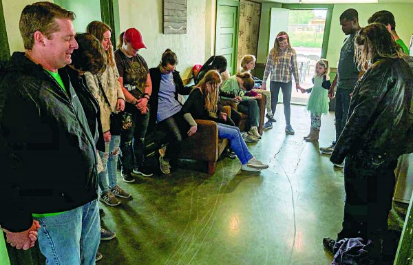At the Greenhouse, home of Central Phoenix Urban Ministry, Sean McClue, left, leads a prayer for a group of university students during a campus ministry service retreat.