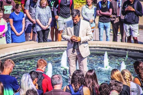 Michael Ross, new president of Ohio Valley University in Vienna, W.Va., prays with students by a campus fountain.
