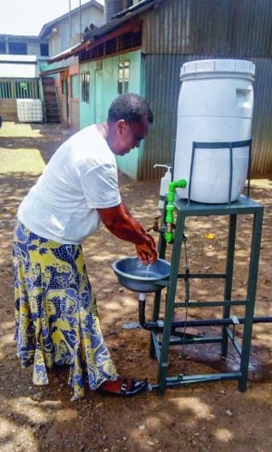 A woman in Kenya uses a pedal-operated hand-washing station designed by minister Nyabuto Marube. The minister buys water containers from families who use the money to purchase food.