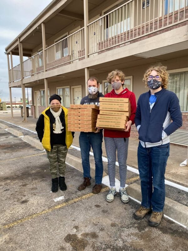 Luke Hartman and his sons, with Delisa Herbert-Jones, deliver pizzas to unhoused friends in hotel rooms during a cold snap.