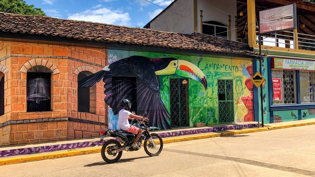 A motorbike speeds by one of the murals near the Campamento town square.