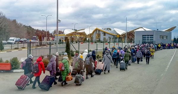 A long line of Ukrainians walks toward the Polish border checkpoint, fleeing the war in their homeland.