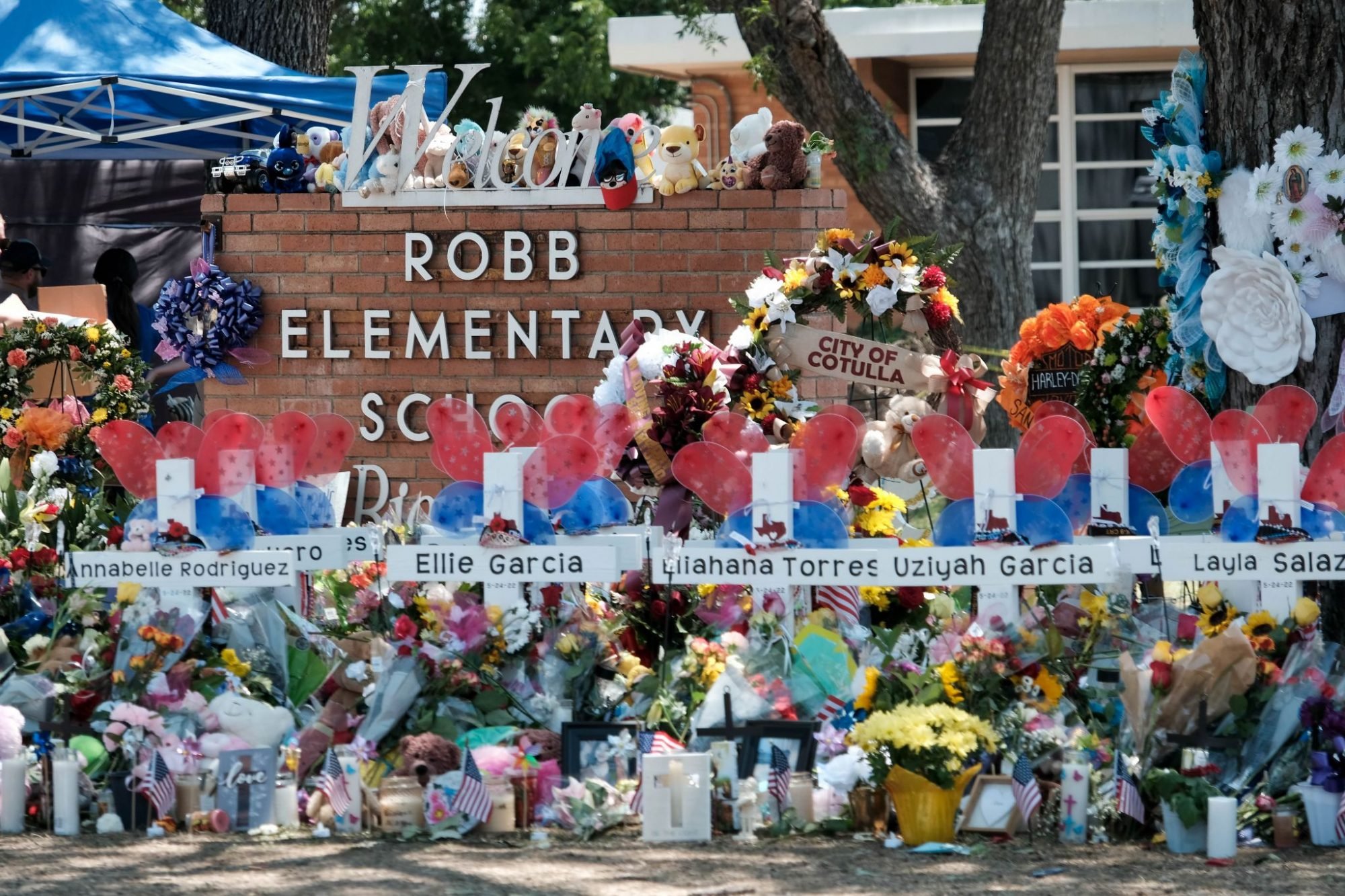 Memorial crosses bearing the names of those killed in the shooting sit in front the Robb Elementary School welcome sign.