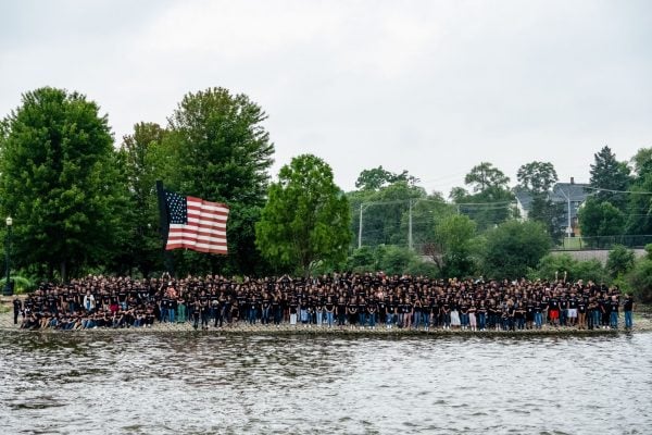 Attendees at the Reunión Juvenil Nacional conference pose for a group photo in front of an American flag sculpture on Walton Island in Elgin, Ill.
