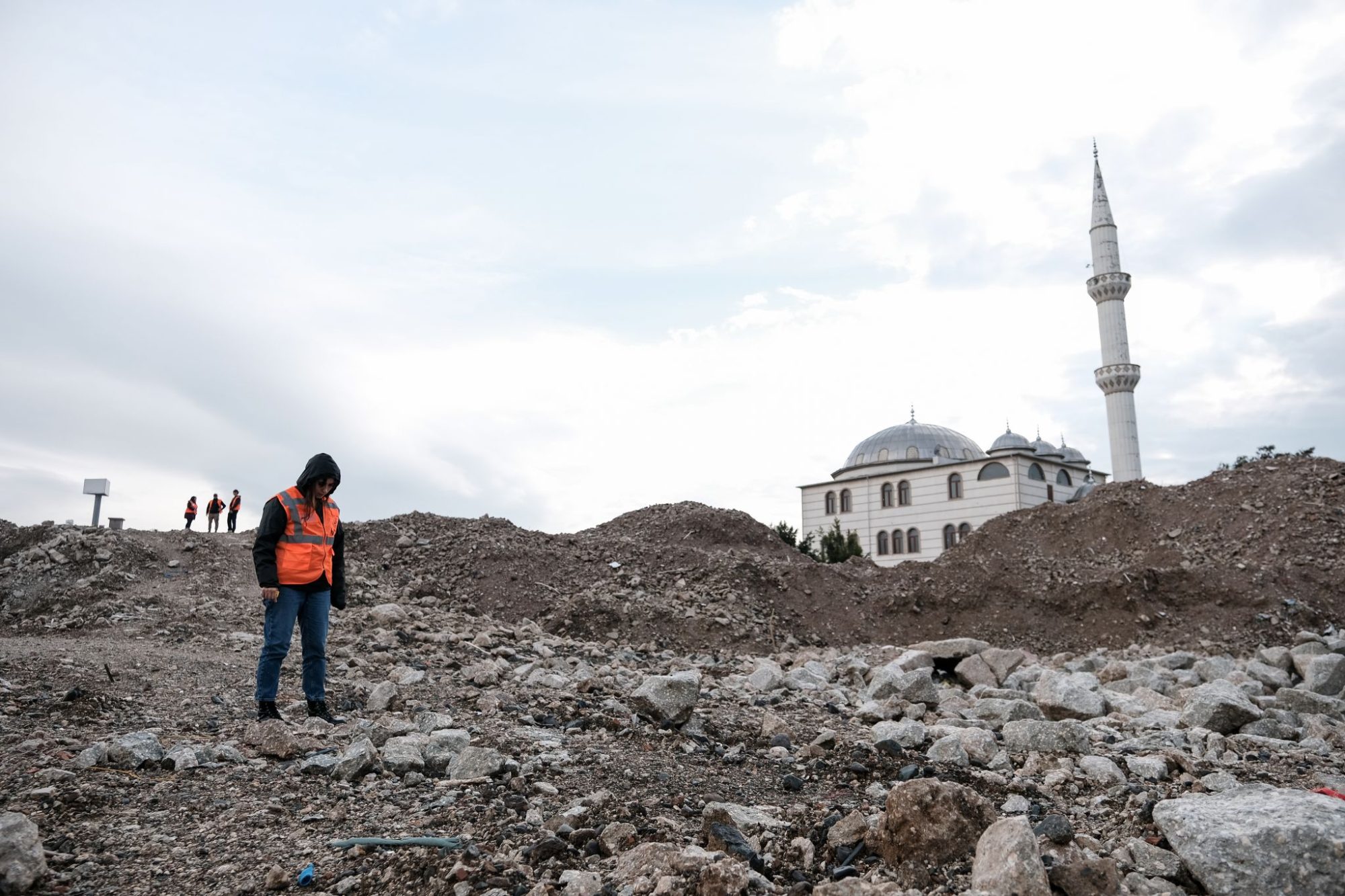 An İlk Umut Derneği worker stands on what remains of an apartment building in Antakya, Turkey.