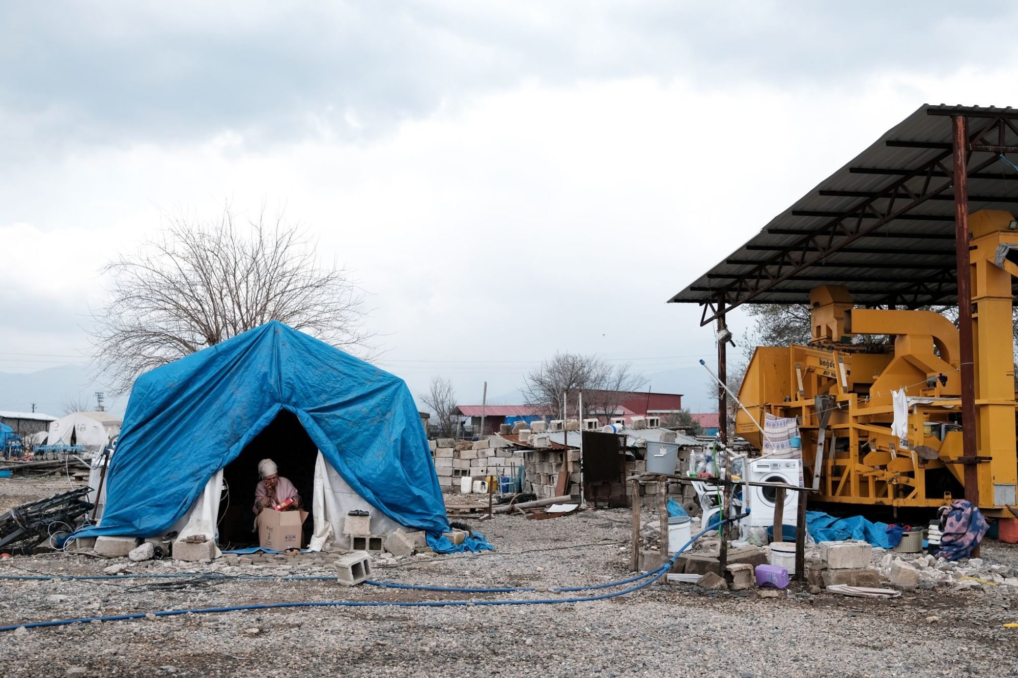 A woman living in a tent in the Gaziantep Province opens a hygiene box distributed by İlk Umut Derneği.