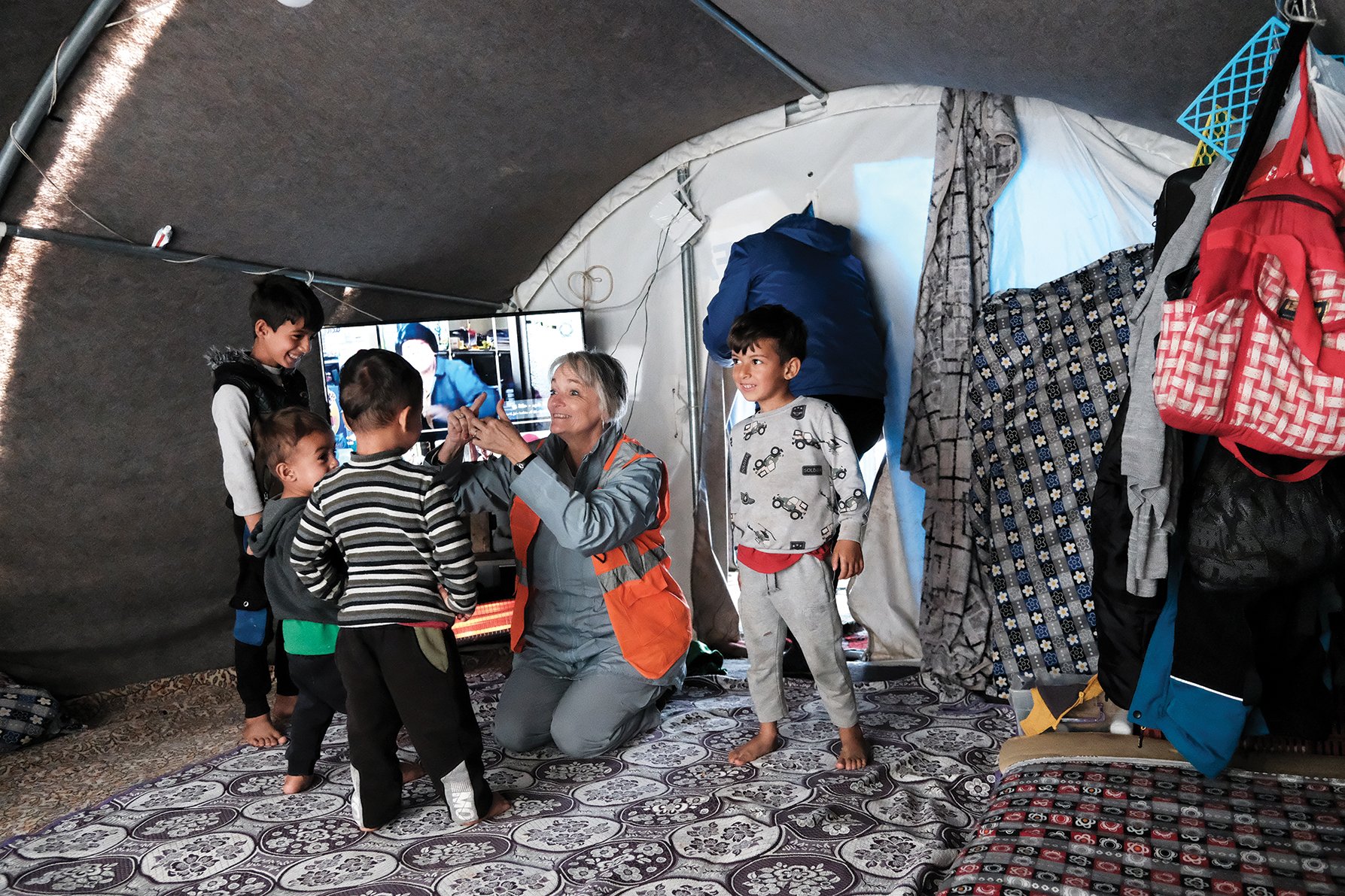 Beverly Dobbs teaches children living in a tent camp how to do the hand motions for the “Itsy Bitsy Spider” song.