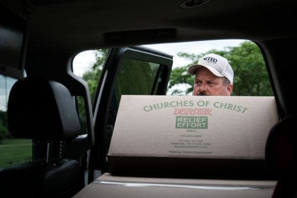 A member of the Vinita Avenue Church of Christ loads a box of food into a family's sedan during relief distribution on Wednesday.