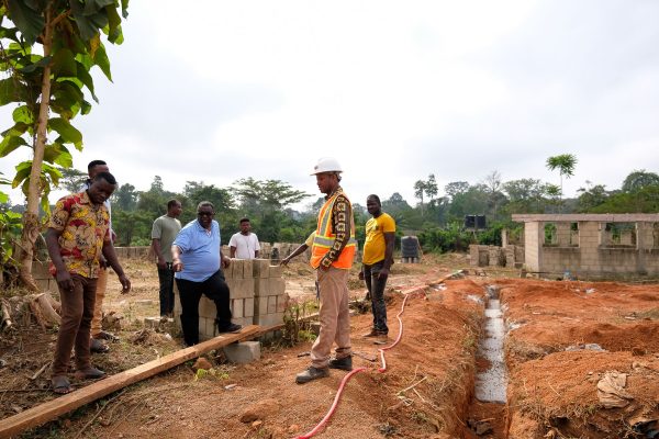 Augustine Tawiah, centers, discusses the construction of the New Debiso girls' boarding school with laborers. 