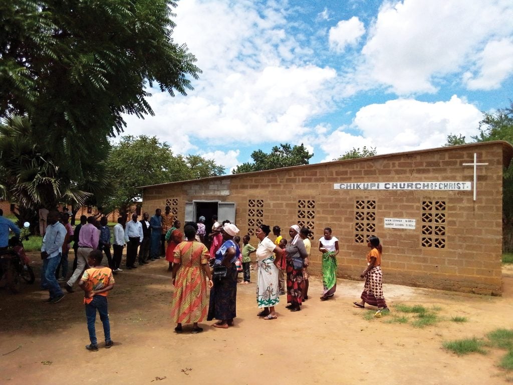 Christians gather outside the meeting place of the Chkupi Church of Christ in Zambia.