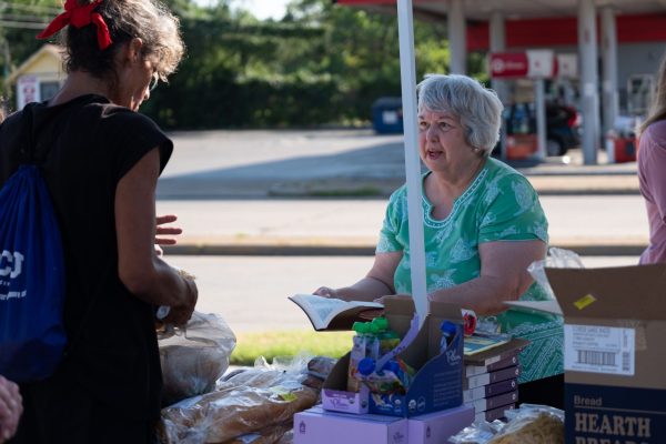 Church member Marsha Fry offers a free Bible to a neighbor during the Bridgewood Church of Christ's regular Saturday food giveaway.