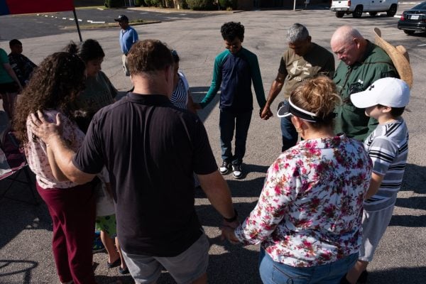 Bridgewood Church of Christ members pray for a neighbor — whose husband recently got out of the hospital — during the congregation's regular Saturday food giveaway.