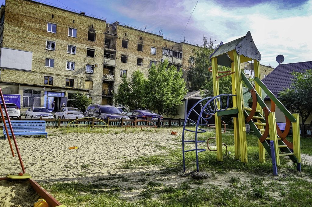 Playground equipment stands in front of a battle-damaged apartment building in Irpin, Ukraine.