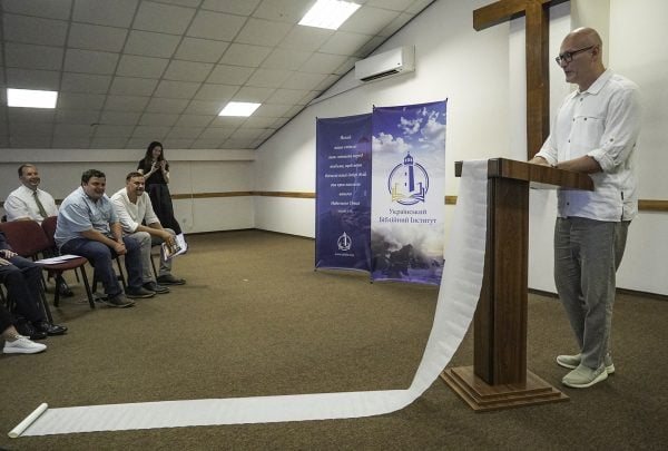 Dmytro Vorobiov unveils his sermon notes during the Ukrainian Bible Institute's graduation ceremony. 