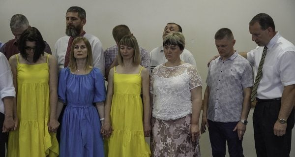 Alexander Maliuga, right, leads a prayer during the Ukrainian Bible Institute graduation.