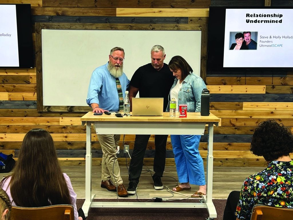 Pat Sheaffer, advancement coordinator for Sunset International Bible Institute's Adventures in Missions program, prays for Steve and Holly Holladay before their presentation.