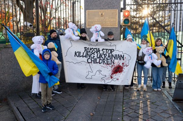 Jeff Abrams and fellow Christians hold a banner and bears stained with red paint symbolizing blood outside the Russian embassy.