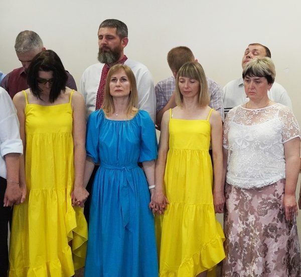 Svetlana Shevchenko, in blue dress, prays alongside fellow Ukrainian Christians during a graduation ceremony of the Ukrainian Bible Institute in 2024.