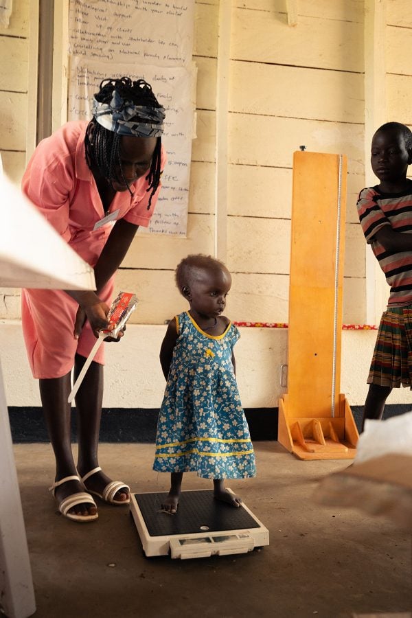 In Uganda, health workers weigh a child during a visit by workers with Mana Nutrition.