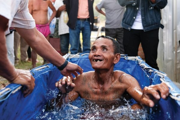 A man emerges from the water smiling after being baptized by Mike Meierhofer in Preah Netr Preah, Cambodia.