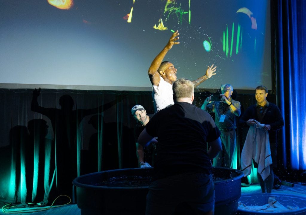 A teen leaps from the waters of baptism at the SonQuest Youth Conference.