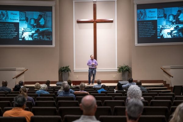 A voice tested by faith 3 MyCelestialApp Mark Adams shows a slide of the Plessy v. Ferguson case on the projector screens during a sermon.