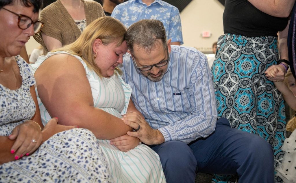 Family minister Logan Cates, right, prays with Dylan Harendt after she came forward on a recent Sunday.
