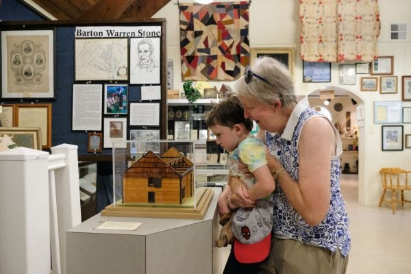Jennie Shirey lifts Emerson Marsala, her 4-year-old grandson, so he can view a miniature replica of the Cane Ridge Meeting House in the Barton Warren Stone Museum in Bourbon County, Ky.