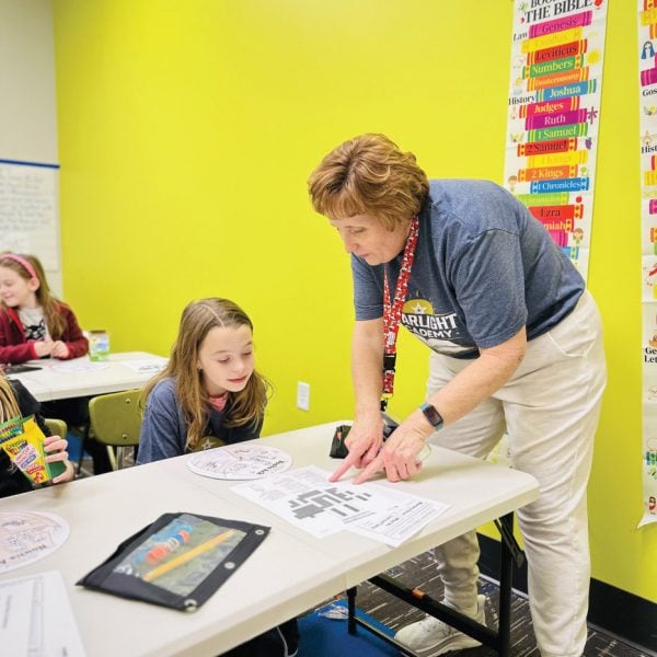 Starlight Bible Academy teacher Stacey Gonzales helps a second grader, Cortlan Benton. 