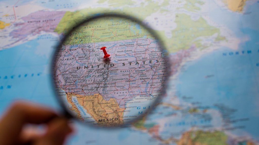 An artist's illustration of a magnifying glass over a U.S. map.